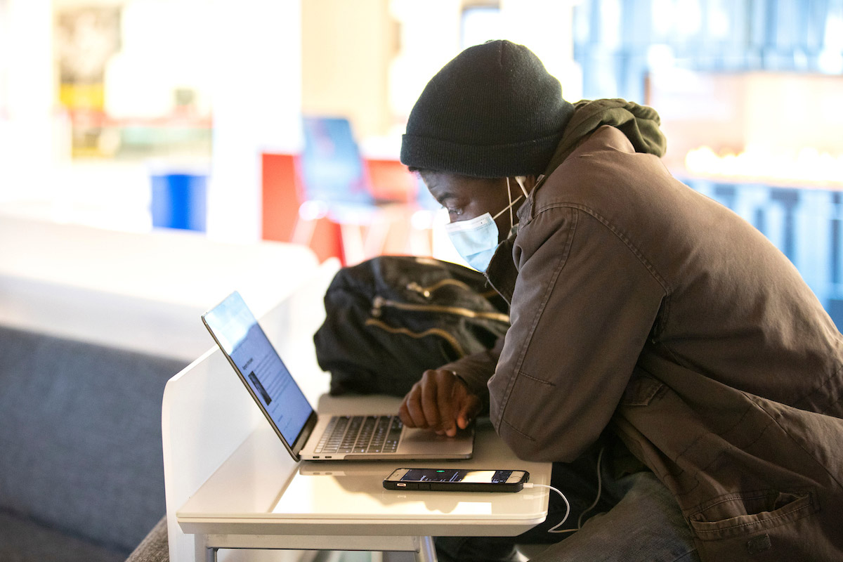 UNO student on computer outdoors