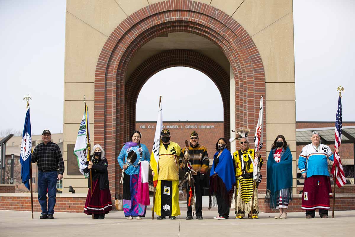 Representatives from the Ponca, Winnebago, Omaha, Santee, and Dakota Nation pose for a photo following the grand entry and presentation of flags at the Annual Wambli Sapa Memorial Pow Wow at UNO. 