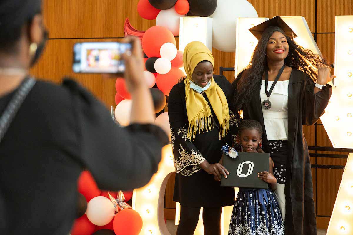 A mother and her daughters celebrate at a UNO Grads sign following UNO's May 2021 commencement.