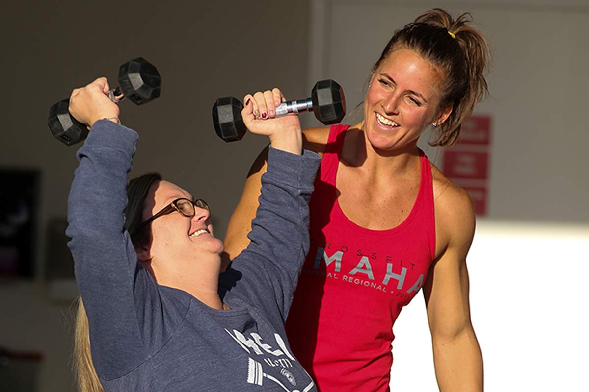 Taryn Schaff lifts weights with the help of a CrossFit coach.