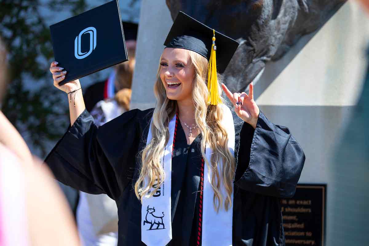 A graduating student poses with their diploma cover