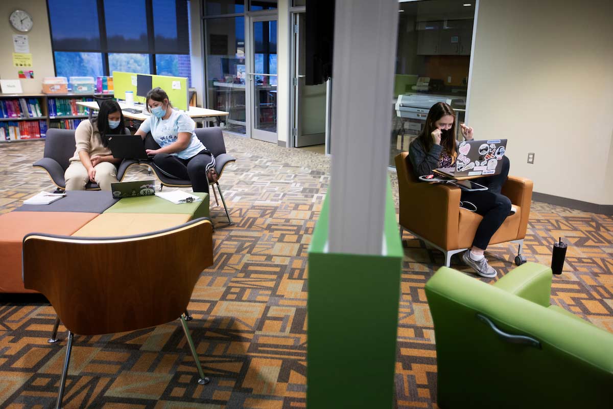 Students sit in a communal area and talk with families over Zoom.