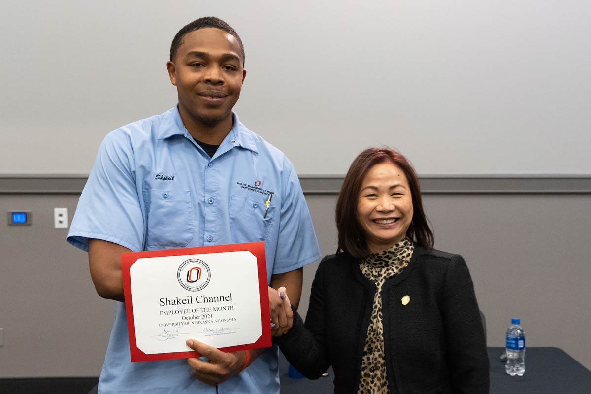 Shakeil Channel holds his Employee of the Month Award next to Chancellor Joanne Li