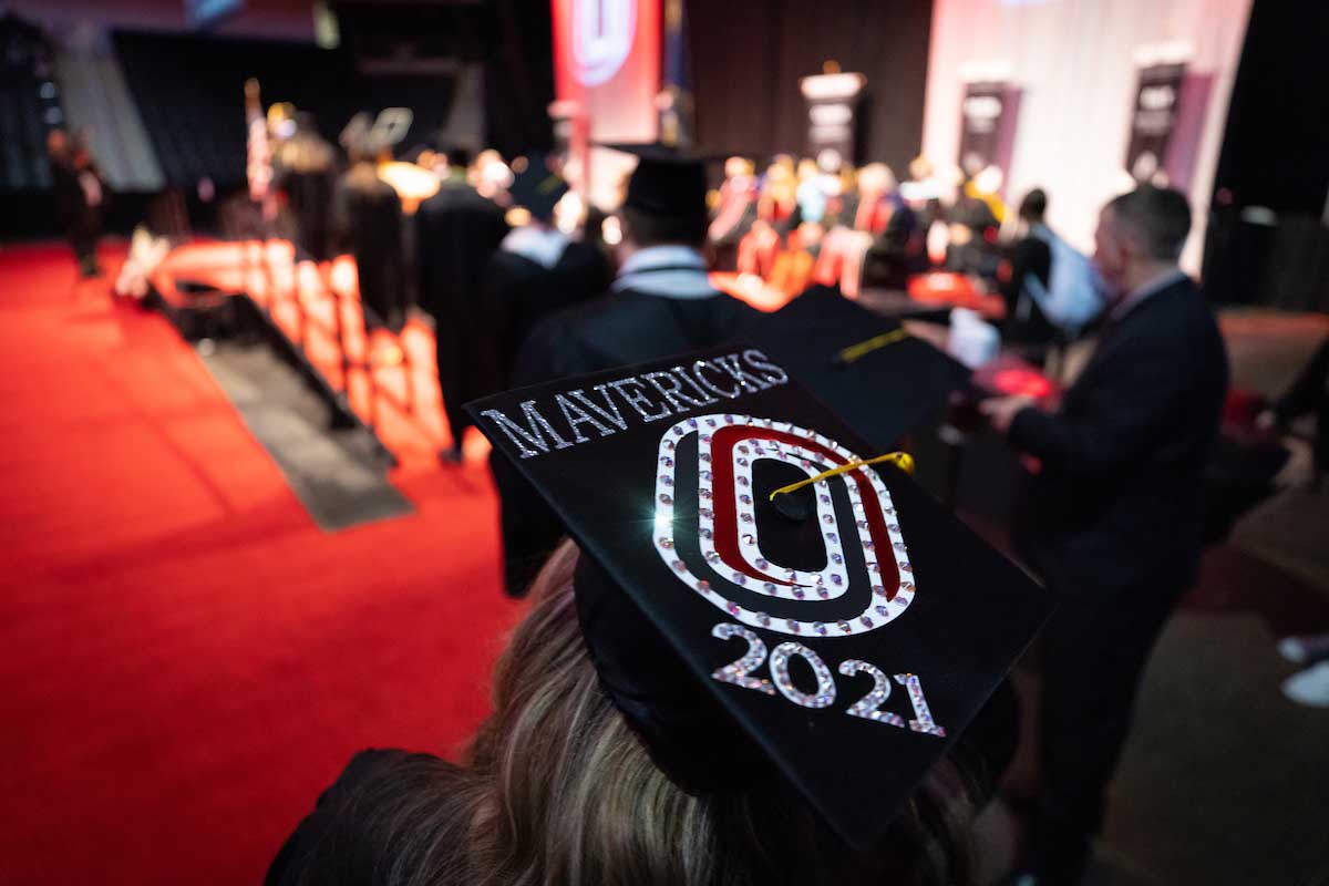 A student prepares to walk across the stage with a "UNO" designed cap.