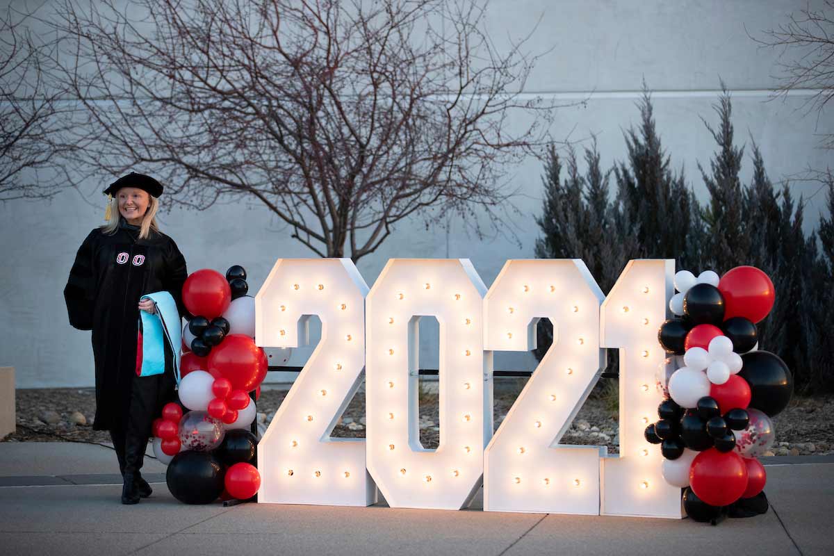 A student poses for a photo next to a '2021' sign