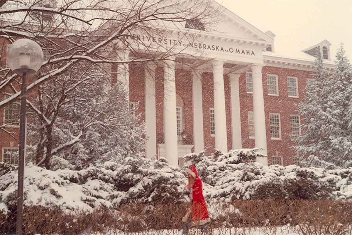 A woman in a red coat walks through snow near ASH.