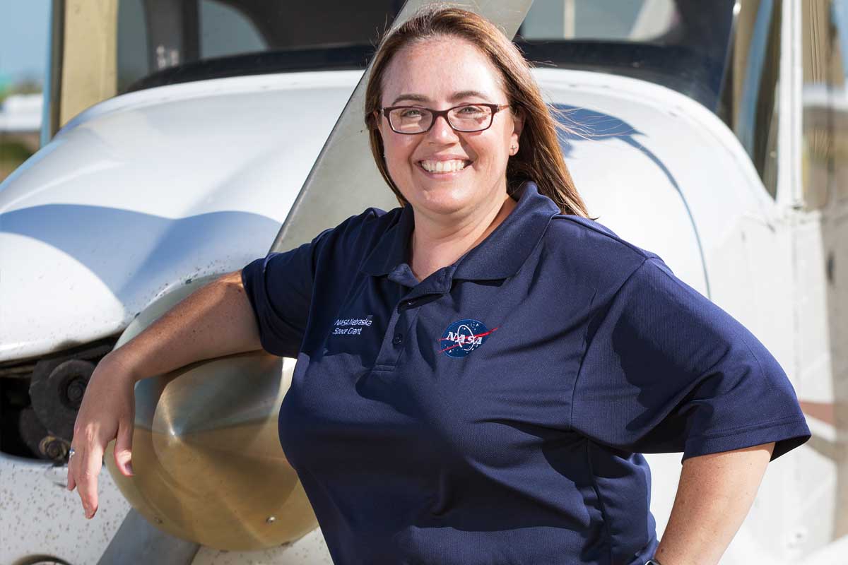 Michaela Lucas, assistant director of the NASA Nebraska Space Grant, stands in front of a plane