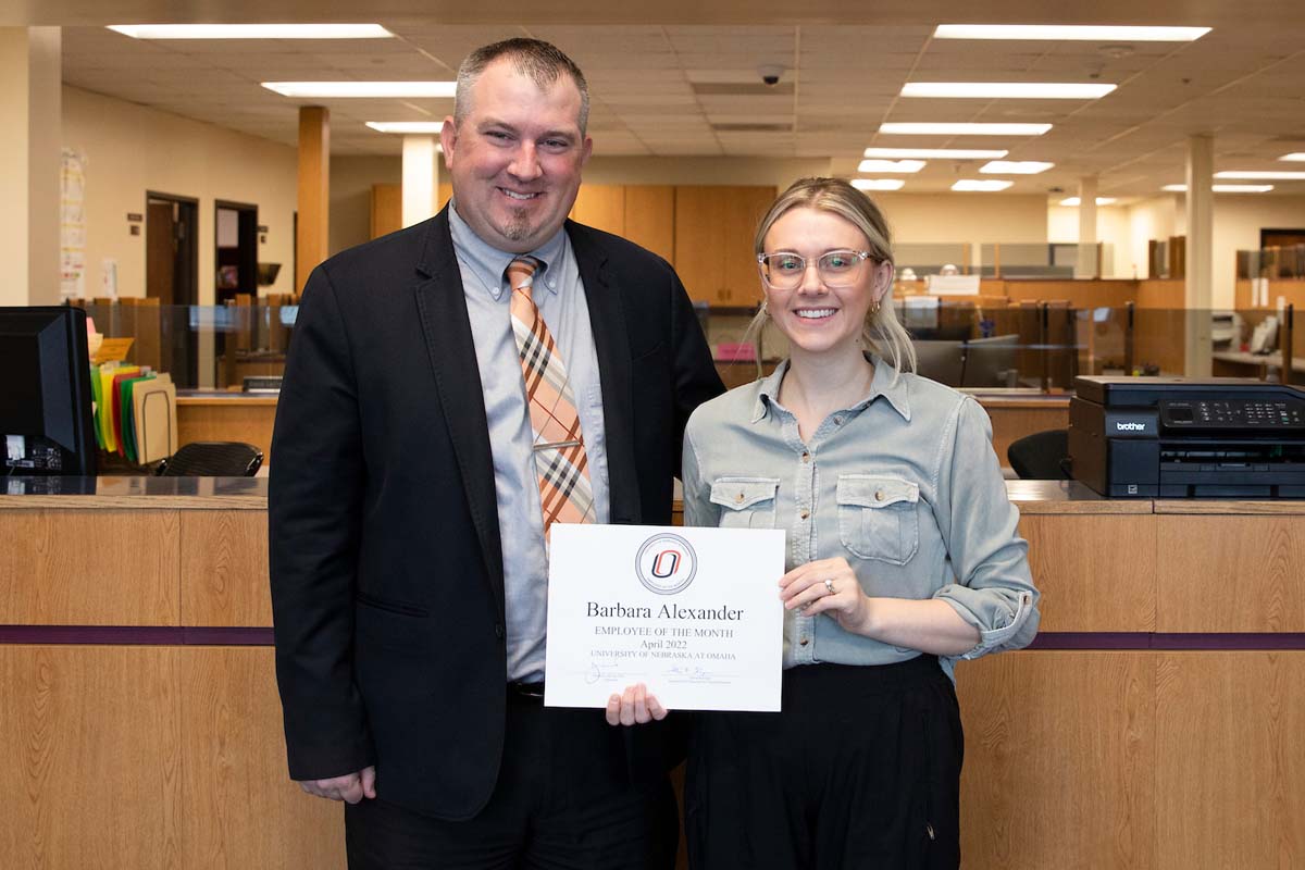 Barbara Alexander stands next to her boss, Matt Schill, holding her "Employee of the Month" certificate.