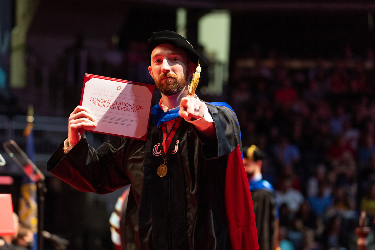 A student shows the inside of his diploma congratulating students on their achievement