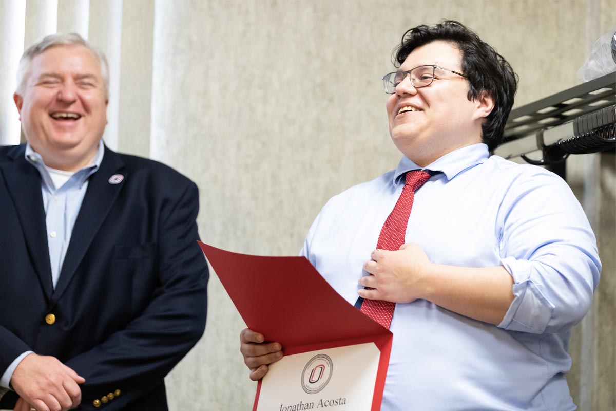 Assistant Vice Chancellor of Human Resources Steve Kerrigan laughs along with Jonathan Acosta, who is holding his Employee of the Month certificate.