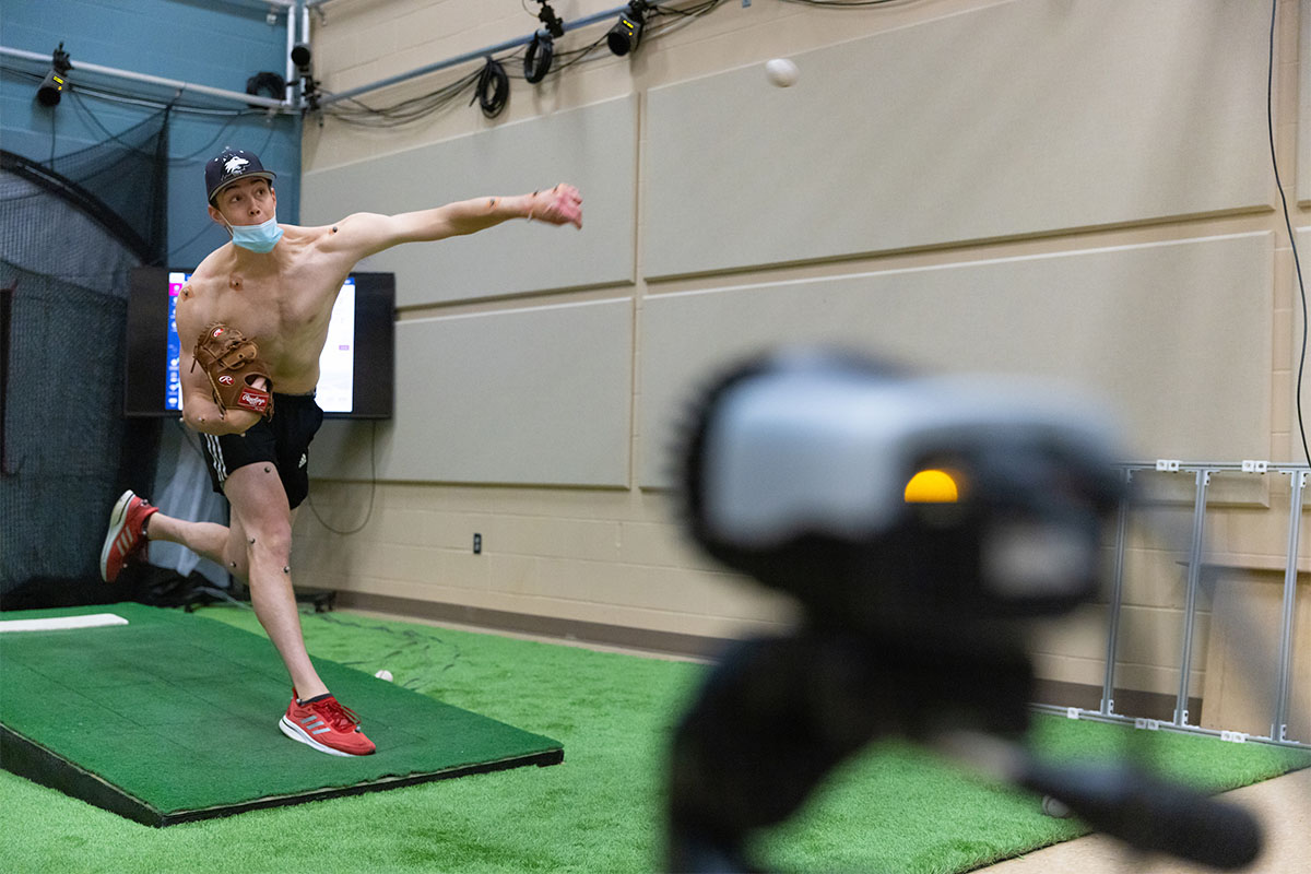 Seebach throws a pitch while wearing motion sensors as biomechanics researchers track his motion.
