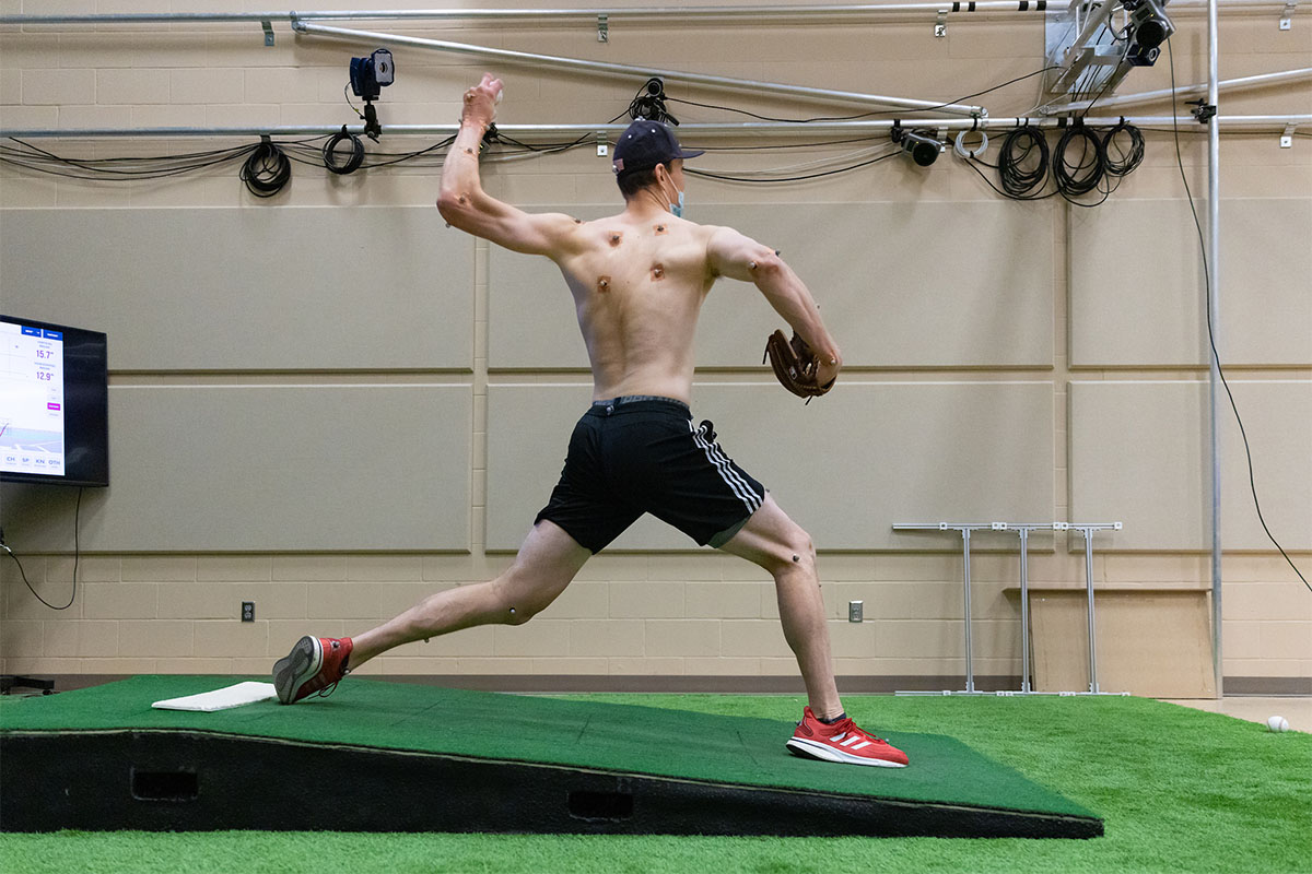 Seebach throws a pitch while wearing motion sensors as biomechanics researchers track his motion.