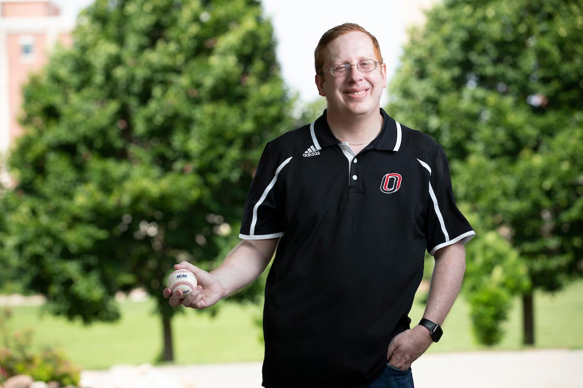 Andrew Swift stands by Arts and Sciences Hall with a baseball in hand