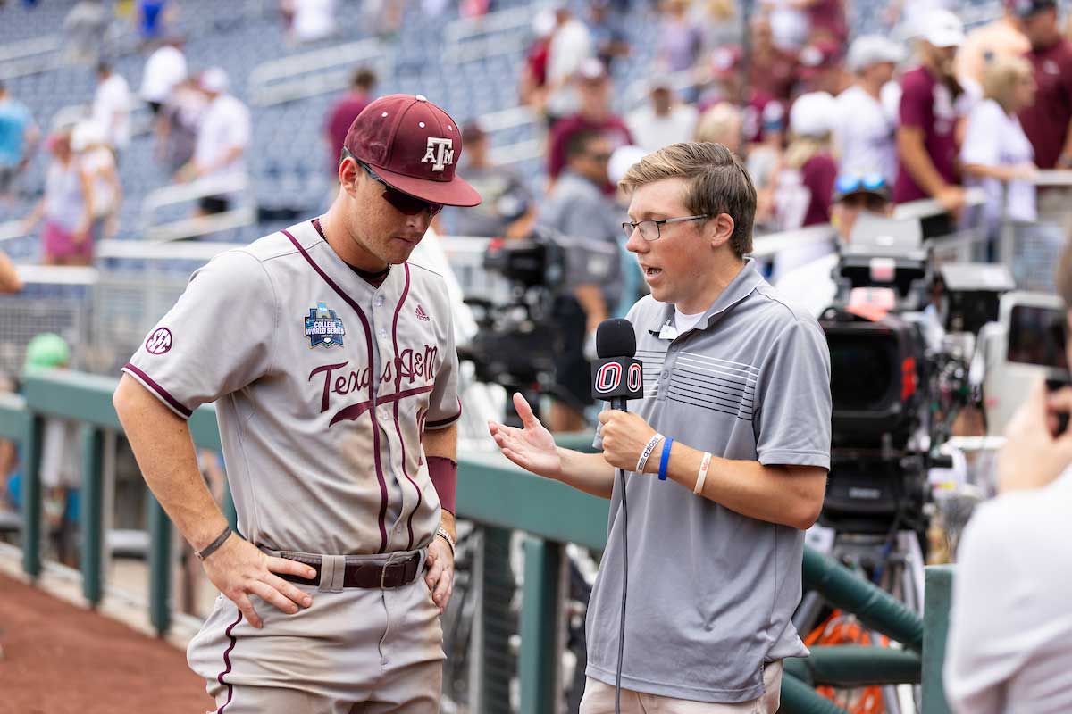 UNO student Jack McGonigal of MavRadio interviews a player from Texas A&M on the field of Charles Schwalb Park after a game of the College World Series.