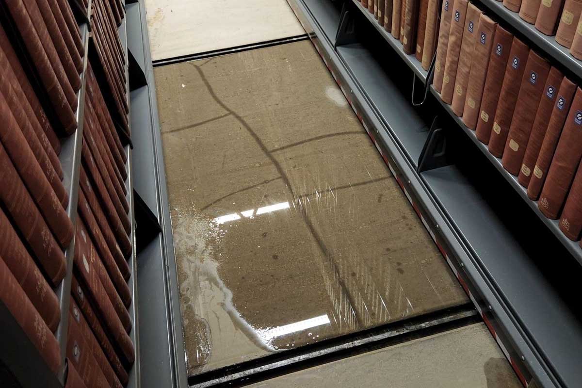 A pool of water has collected between two library shelves.