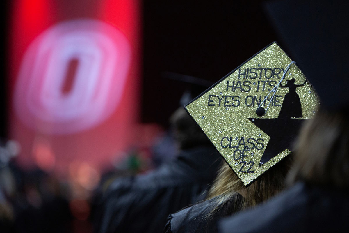 A graduate at UNO's May 2022 commencement ceremony wears a mortar board that reads "history has its eyes on me, Class of 22," playing on lyrics from the musical "Hamilton."