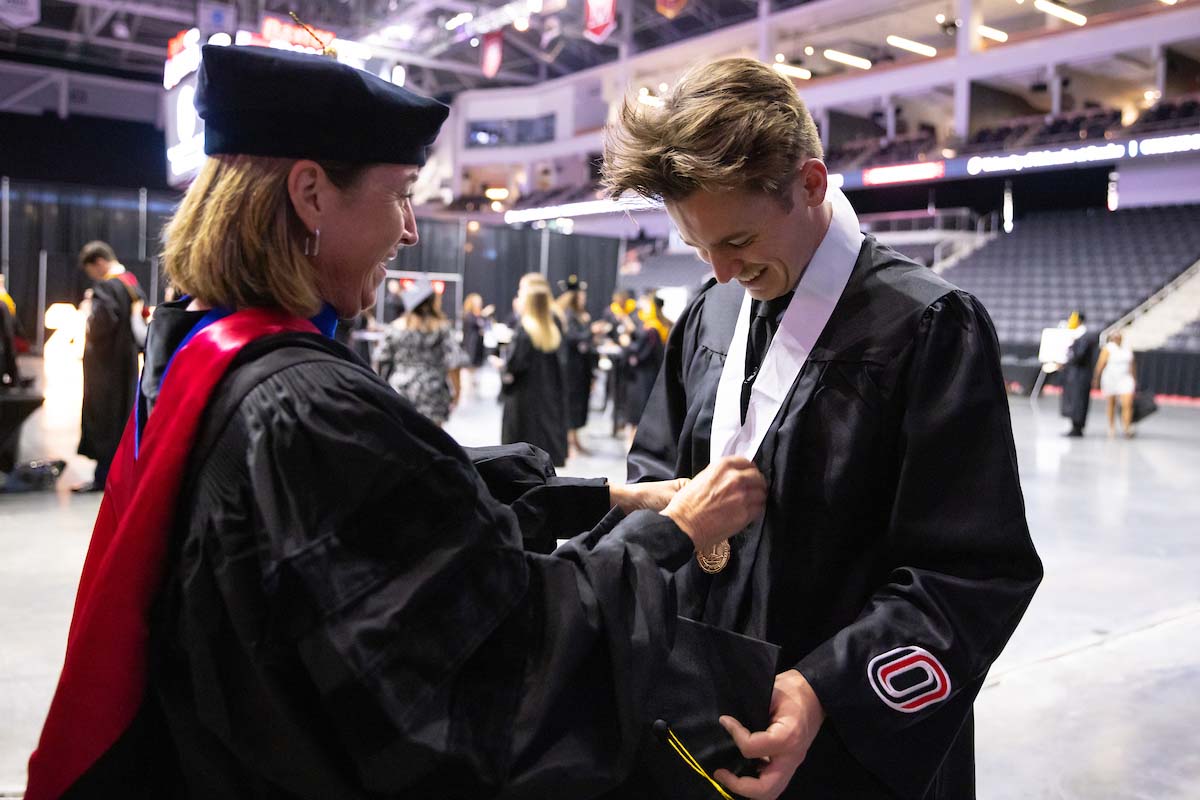 Becky Lutte puts a medal on her son Scott at Commencement