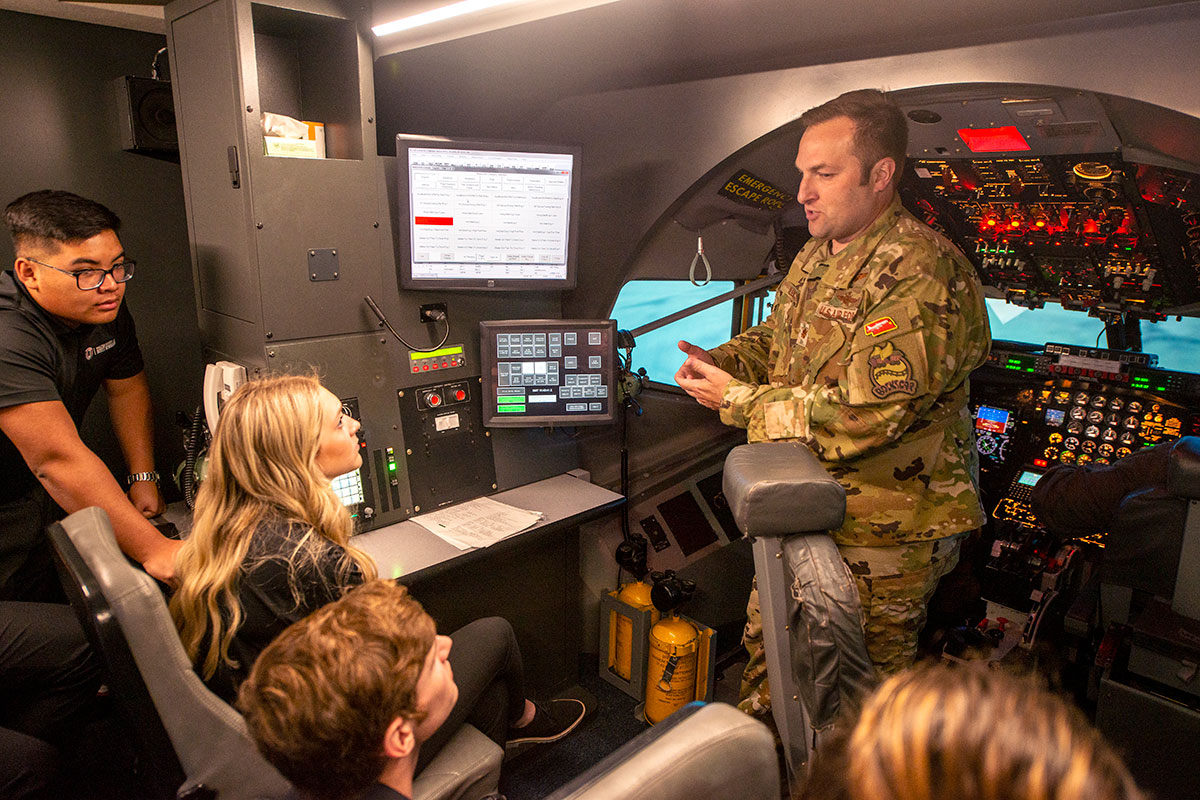 Bella Donovan, left, a UNO Walter J. Scott scholarship winner, and Capt. Erin Bleyl, 45th Reconnaissance Squadron right, gaze into the cockpit of the flight simulator after Donovan completed training on how to land an RC-135. Donovan is the lead student on creating an app for use on the aircraft. (U.S. Air Force photo by D.P. Heard).
