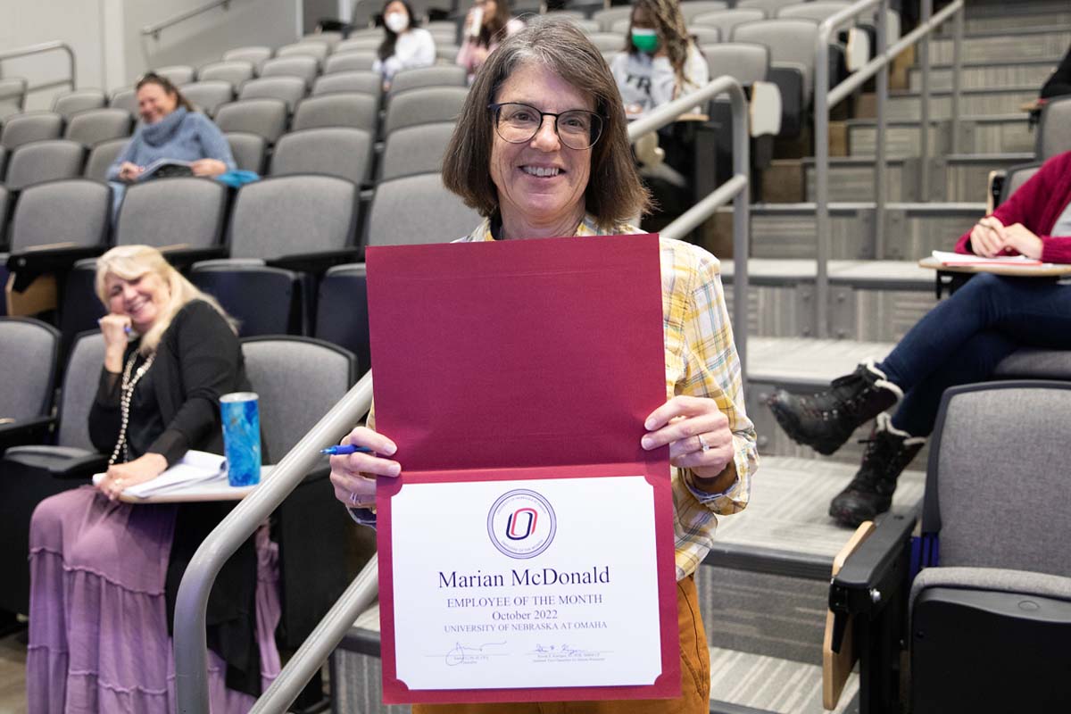 A smiling Marian McDonald holds up her "Employee of the Month" certficate