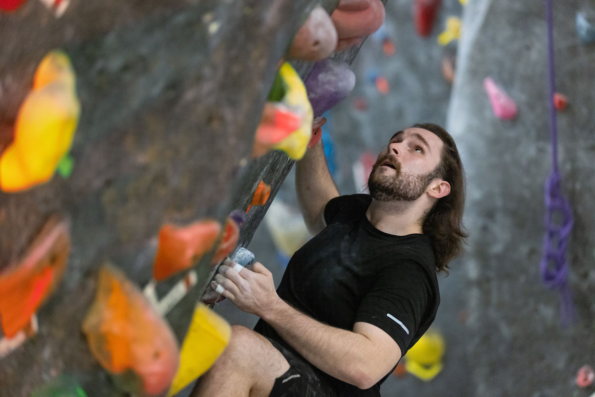 UNO student, Joseph Wiese, half-way up the climbing wall at UNO's H&K Wellness Center