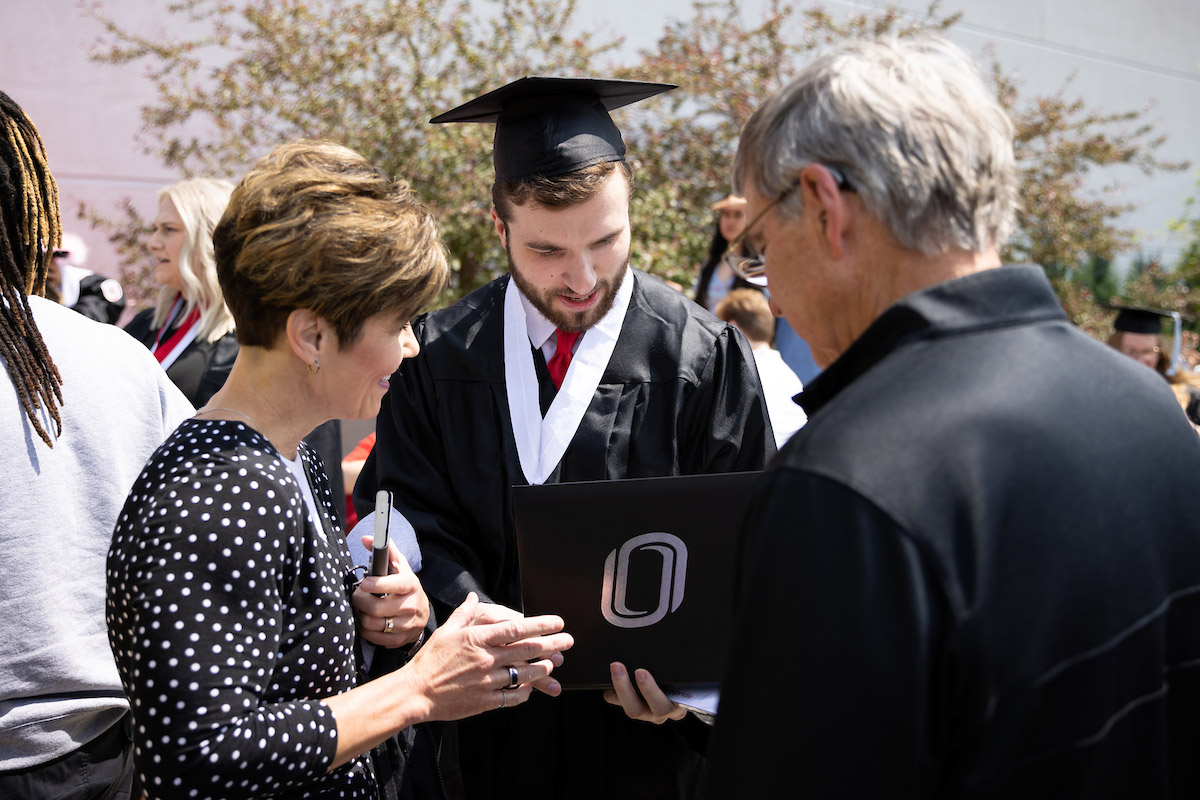 A student looks at his new diploma with his loved ones
