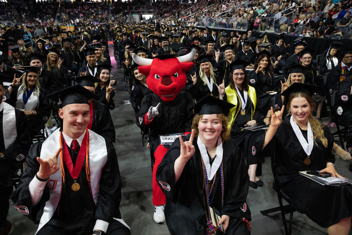 Durango surrounded by fellow graduates showing the Mavericks sign