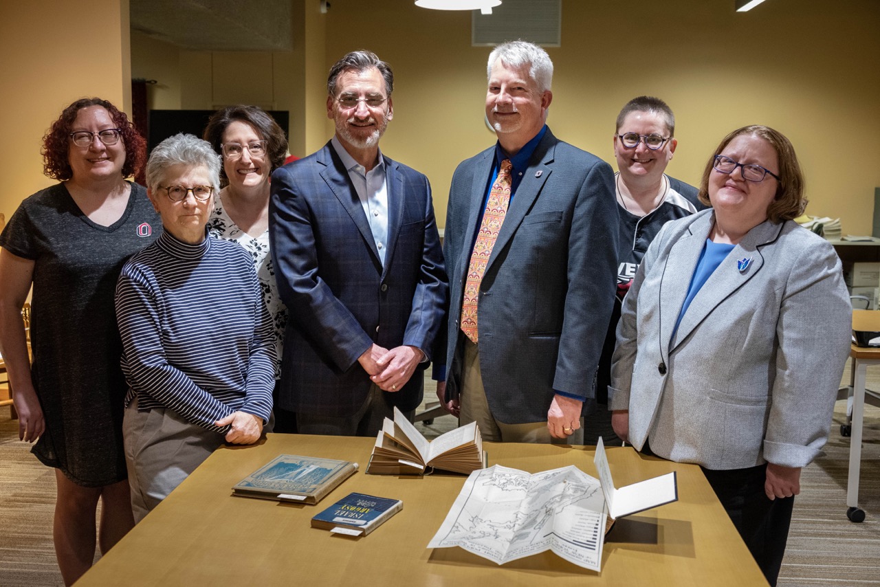 Representatives from UNO and the Jewish Federation of Omaha stand behind a table displaying some books and select works from the Special Kripke-Veret Collection, which will be preserved and publicly available at UNO.