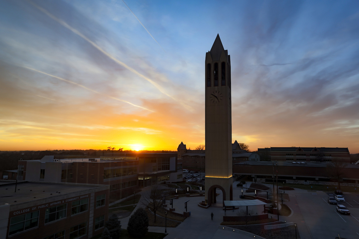 A wide shot of the sun setting behind campus, with the bell tower as the focal point.