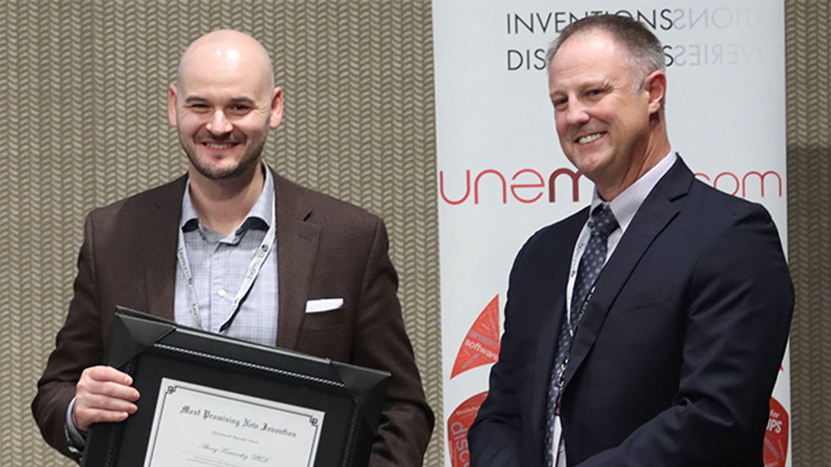Alexey Kamenskiy, Ph.D., professor and chair of biomechanics at UNO, accepts the award for Most Promising New Invention from Michael Dixon, Ph.D., president and CEO of UNeMed, on behalf of the research team behind the optimized vascular stent.