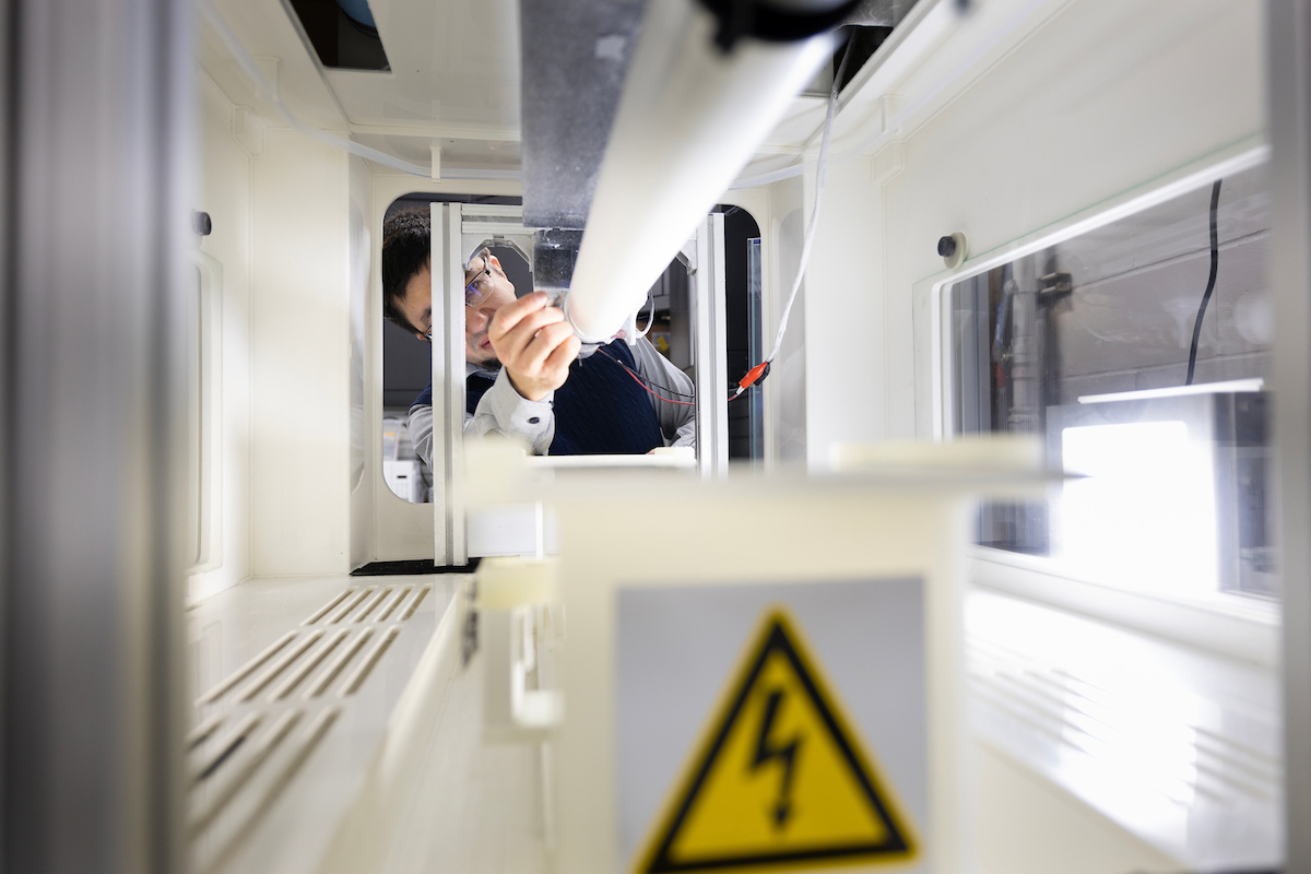 Yury Salkovskiy works in the materials lab taking off cloth created by laying material over a cylindrical tube using an electrical field.