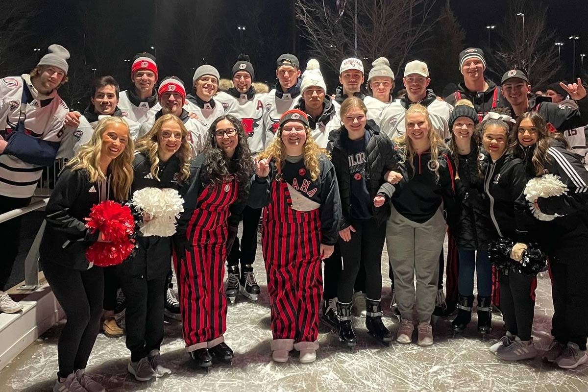 Students posing with Omaha Hockey at the skating ribbon