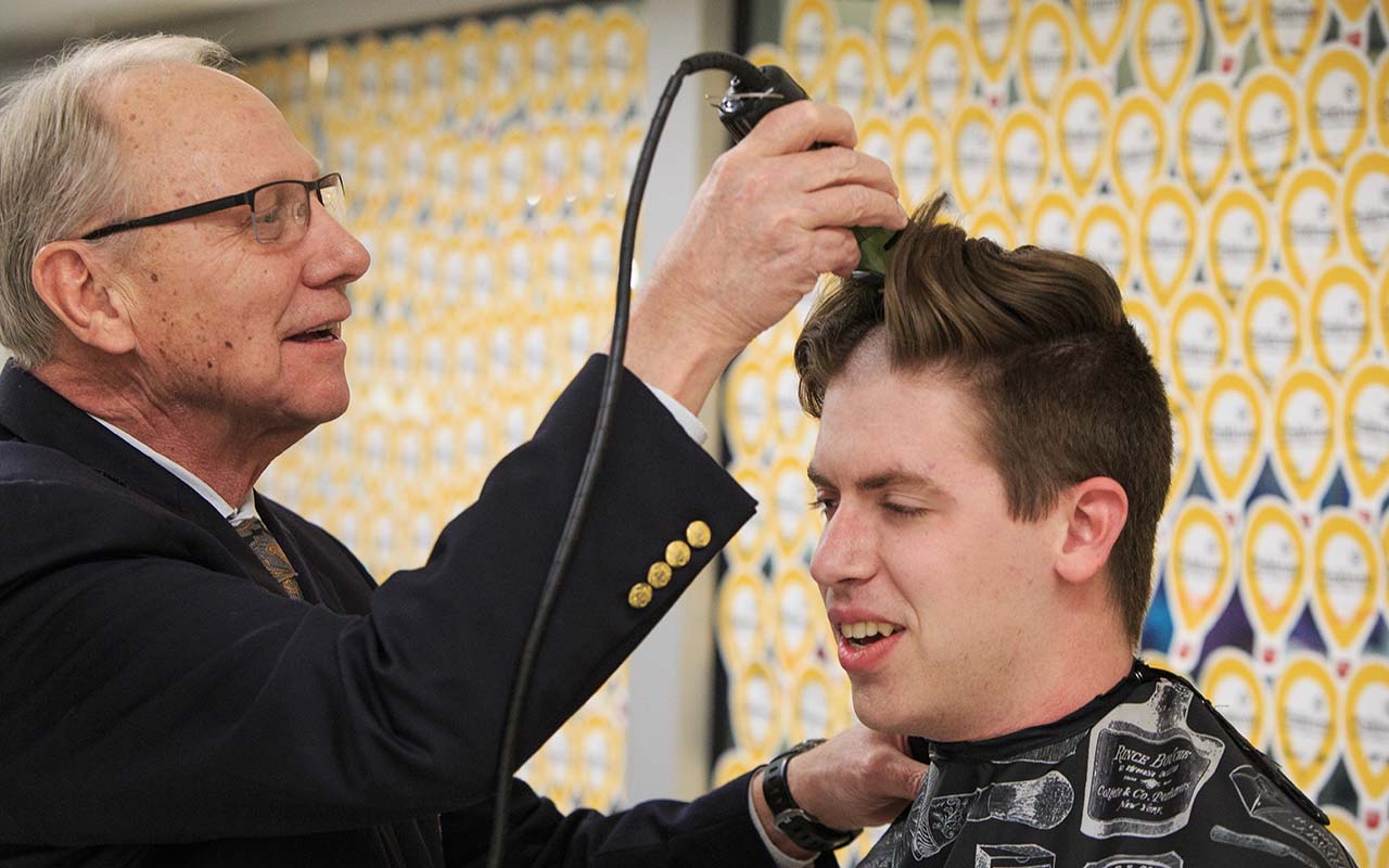 Christensen smiles as he shaves the head of 2016 Student Body President/Regent Patrick Davlin after $5,000 was raised by UNO's Dance Marathon for the Children's Miracle Network.