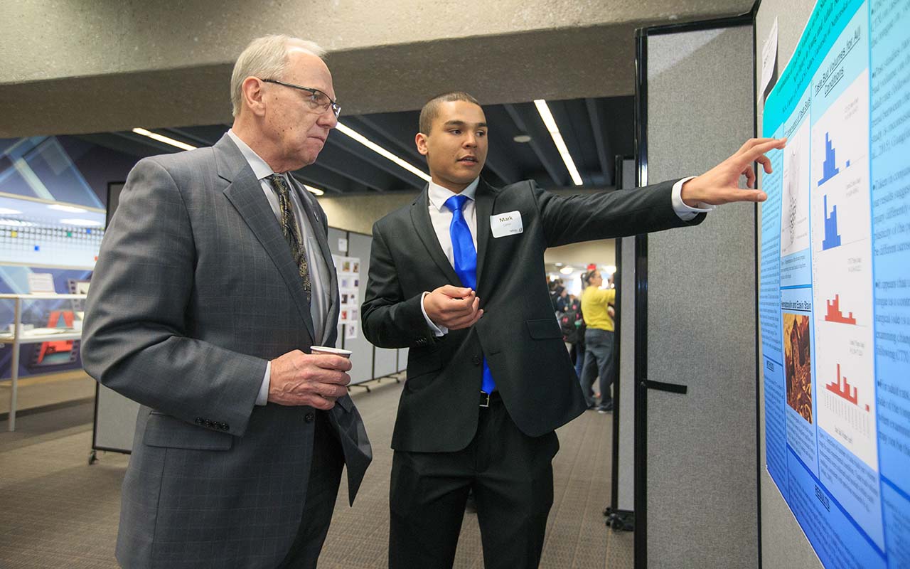 Christensen visits with a student presenting at the Student Research and Creative Activity Fair.