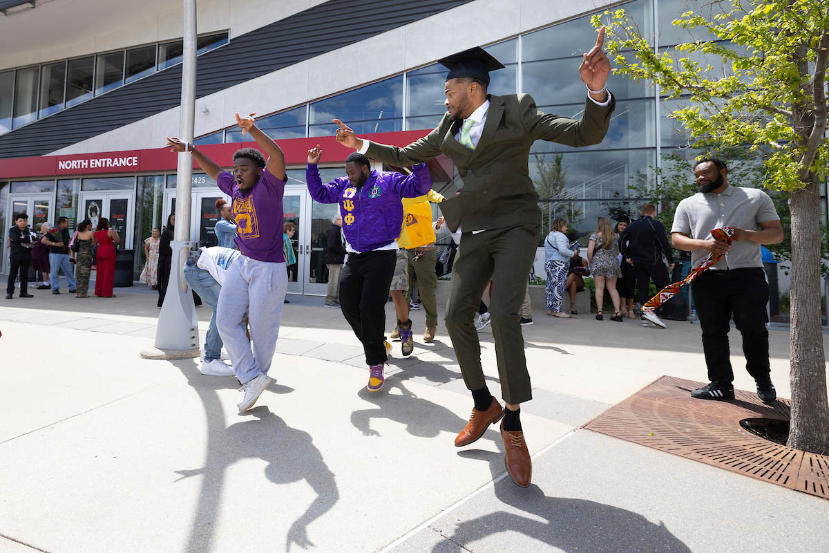 A new grad dances with his fraternity brothers outside of Baxter Arena.