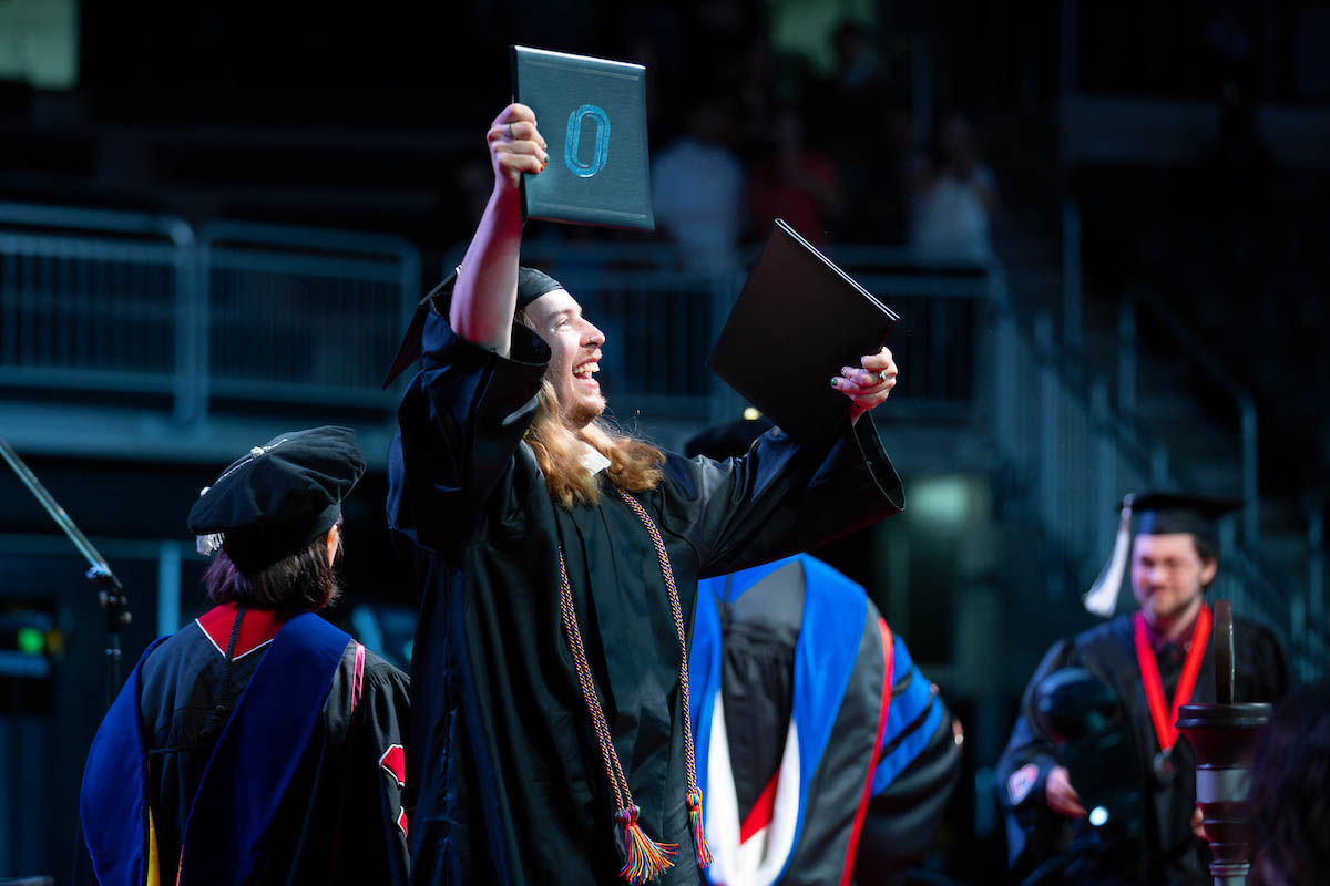 After receiving his diploma, the new alum celebrates by raising it in the air.
