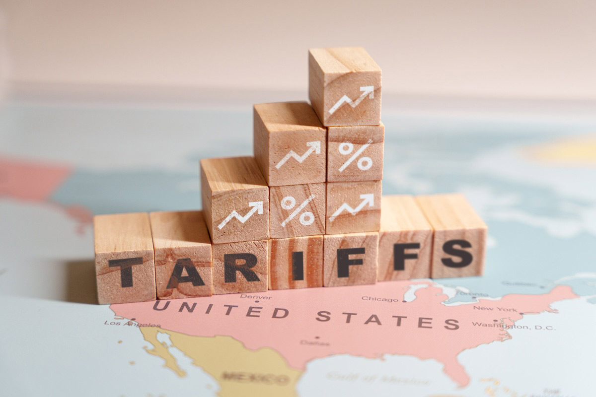 Wooden blocks spelling TARIFFS are placed on a map of North America.