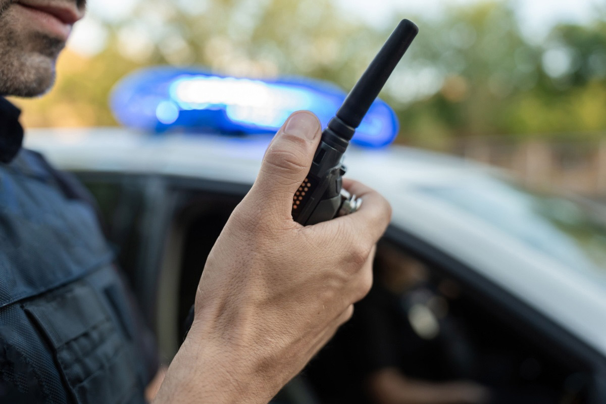 Police officer speaking into walkie-talkie.