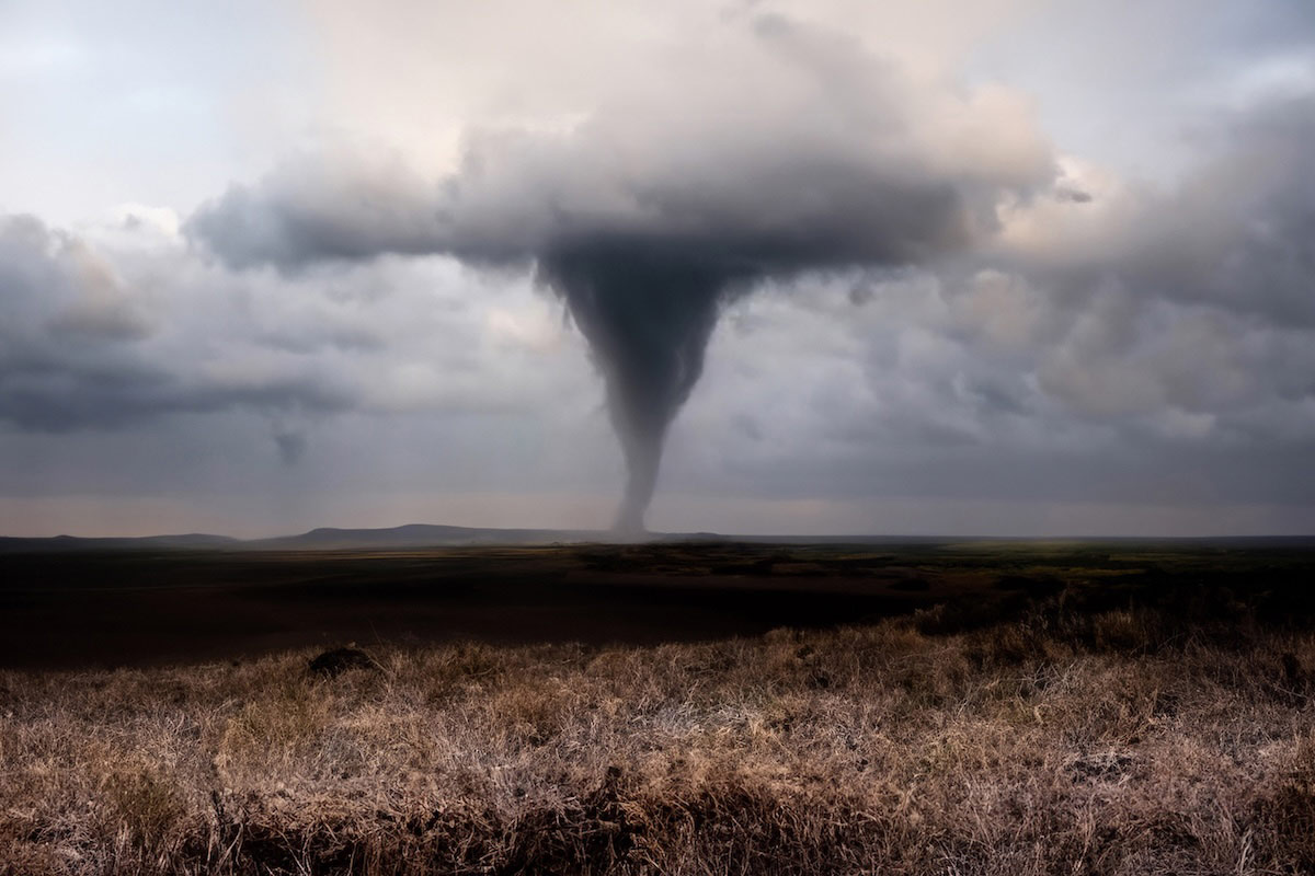 Stormy panorama featuring a tornado over agricultural plains.