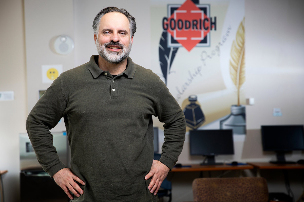 Troy Romero poses for a portrait in front of the Goodrich logo.  