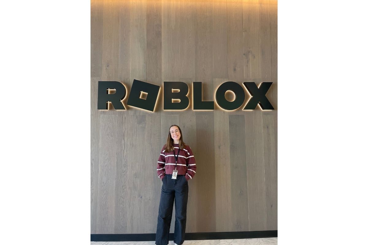 Averie Linnel poses in front of the glowing Roblox sign. 