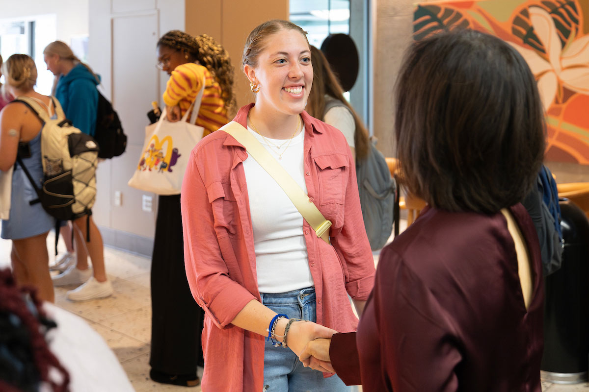 A UNO student smiles while shaking hands with Chancellor Joanne Li during Coffee Talk with Spirit and Tradition at Criss Library’s Starbucks. 