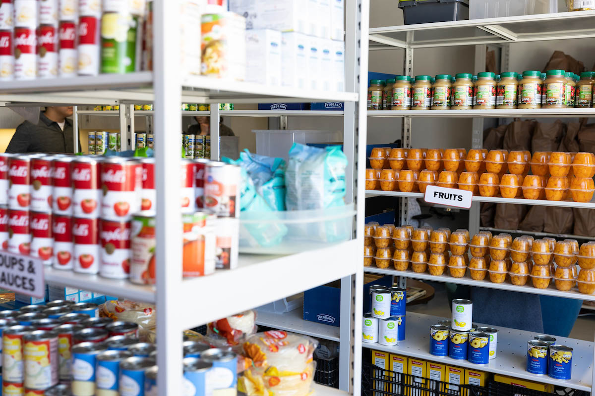 Rows of canned goods, packaged food, and fruit cups arranged neatly on pantry shelves.