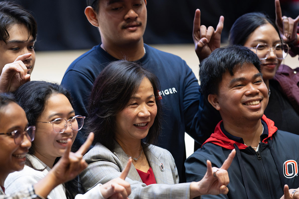 Chancellor Joanne Li smiles and poses with UNO students making the Maverick bull hand sign after the 2025 State of the University Address. 