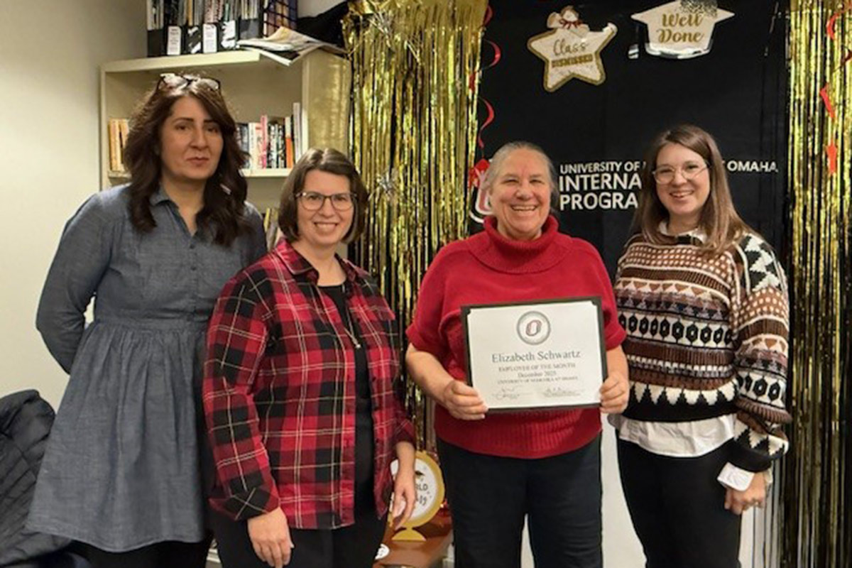 Elizabeth Schwartz poses with her award while her colleagues join her in celebrating.