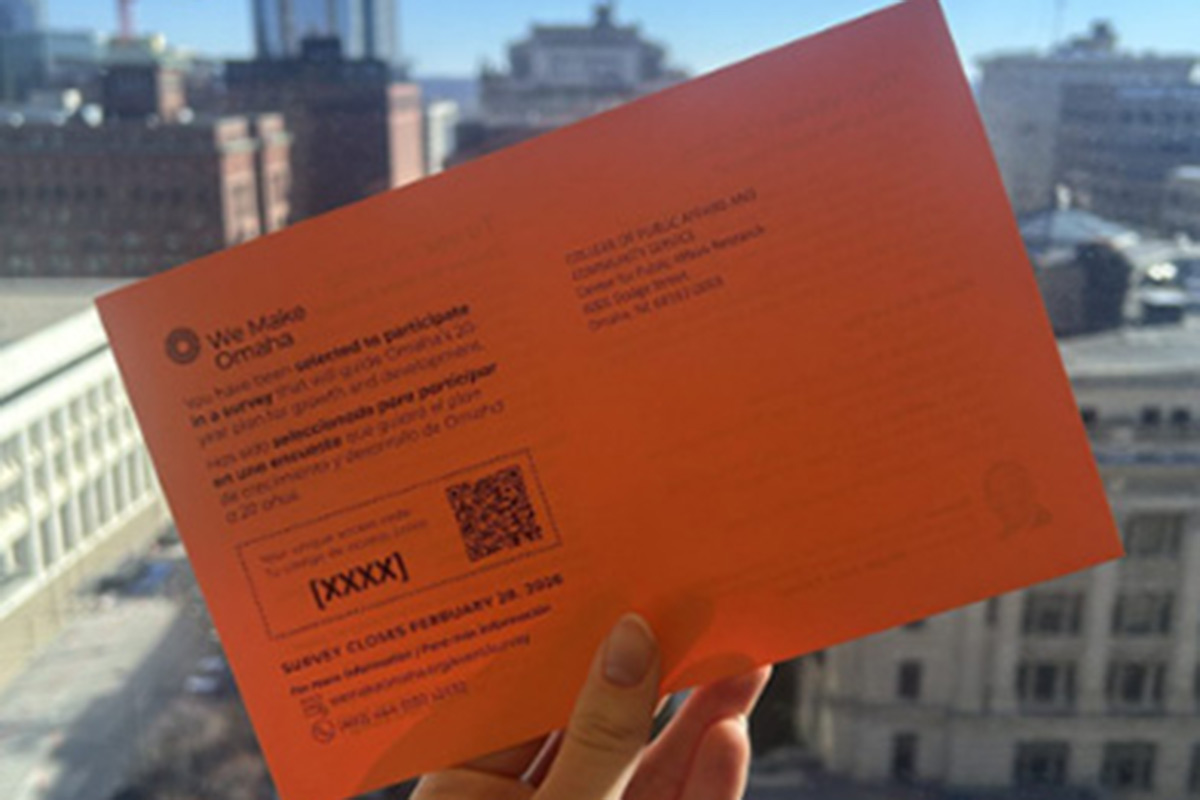 Someone holding up an orange postcard advertising the surveys