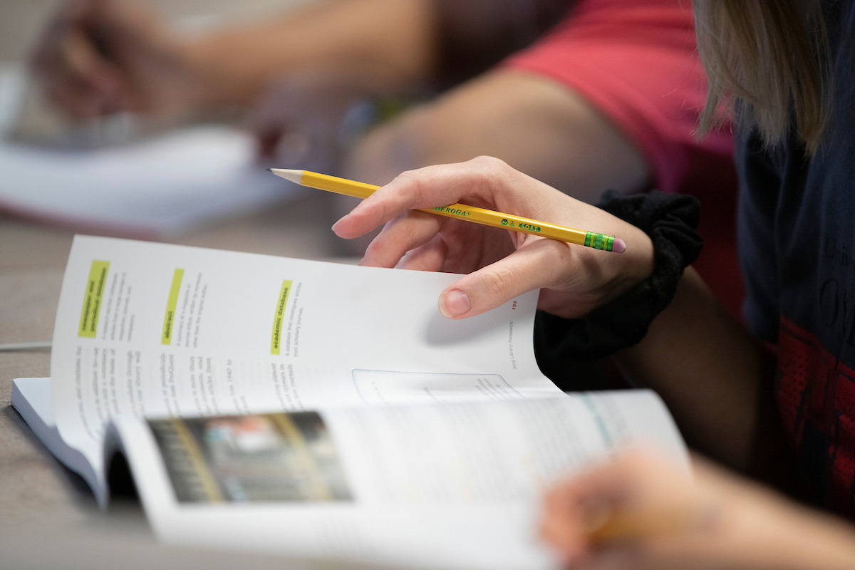 A student reads from a classroom textbook.