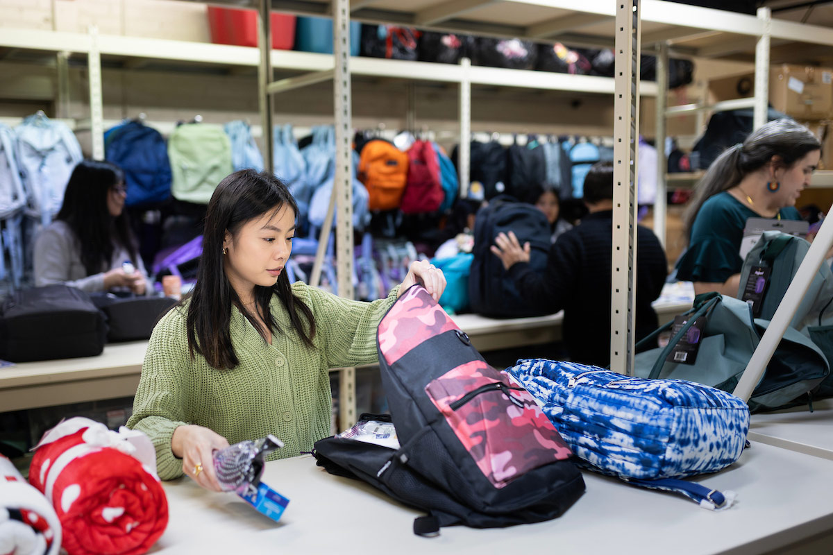 A student puts supplies inside a backpack.