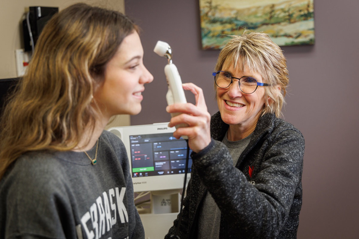 A woman checks a patient's temperature at the UNO Nebraska Medicine Health Center.