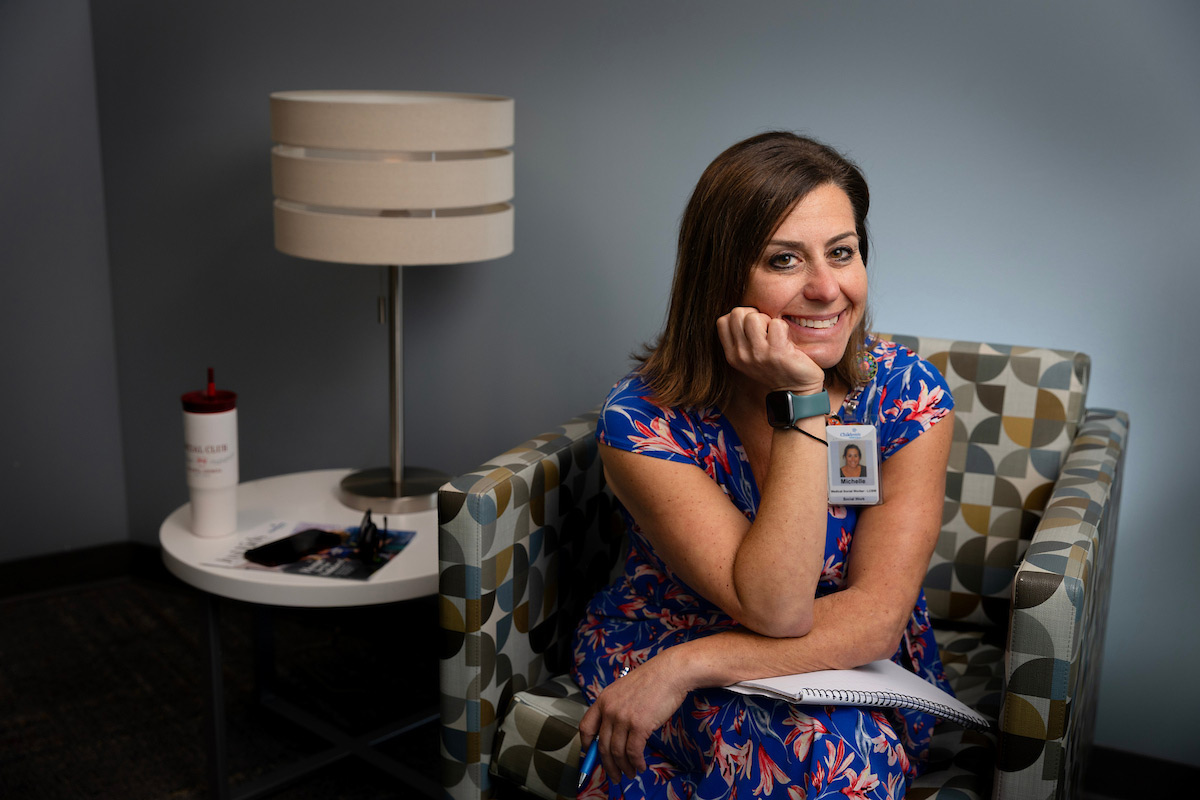 A person sits in a hospital lounge setting and looks to the camera.