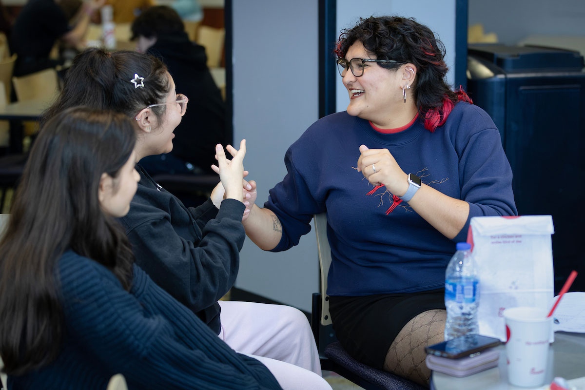 Three students communicate through ASL.  